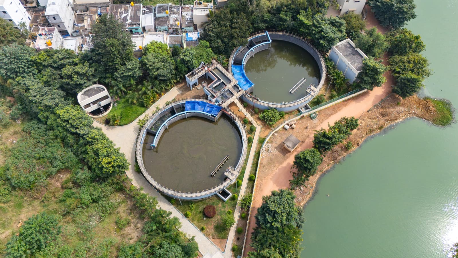 Aerial view of a sewage treatment plant with circular clarifiers and organized water treatment basins.